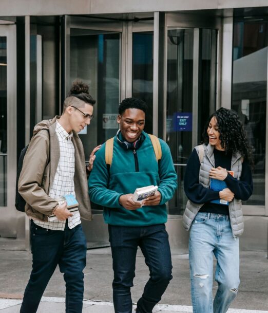 Three students walking out of a campus building