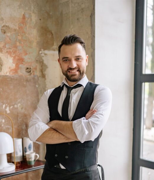 Smiling waiter in a vest and tie standing in a restaurant